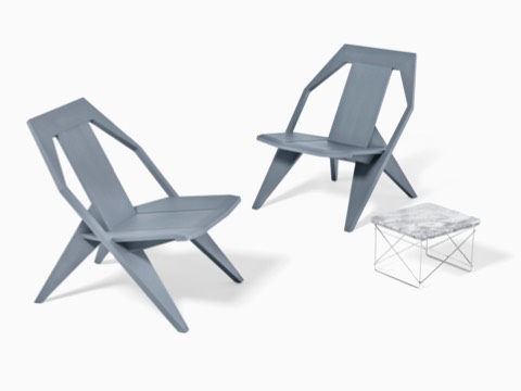 Una base de alambre Eames Mesa baja al aire libre con dos sillas grises para exteriores.