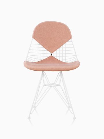 Una silla de alambre Eames con asiento y respaldo “bikini” de dos piezas, tapizada con género rosa claro. Vista desde el frente.