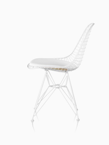 Vista de perfil de una silla lateral de alambre Eames con una almohadilla de asiento de cuero blanco y base de cable.