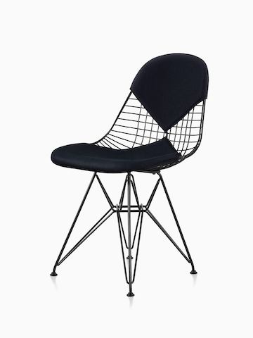 Una silla de alambre Eames en negro con asiento y respaldo “bikini” de dos piezas. La silla presenta una base de alambre en negro. Vista desde un ángulo.