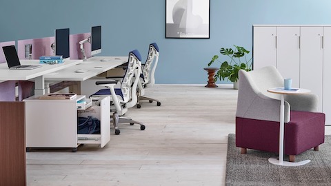 Sillas de oficina Embody azules y superficies de trabajo Renew Link ajustables en altura en un entorno de trabajo de banco.