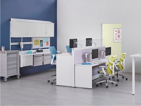 A work environment for healthcare caregivers with seated and standing height workstations and clinical station behind.