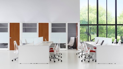 Open workspace with large windows to the outdoors, Ethospace benches, and white Sayl office chairs with red upholstered seats.