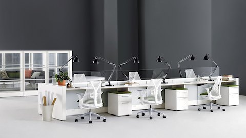 Open workspace with Ethospace benching system, Sayl Chairs with white backs and forest green upholstered seats, and task lighting.
