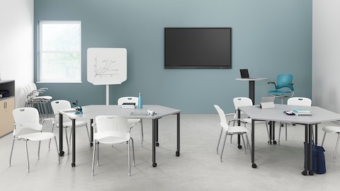 Two pairs of white trapezoidal Everywhere Tables arranged in a learning environment, with white Caper stacking chairs.