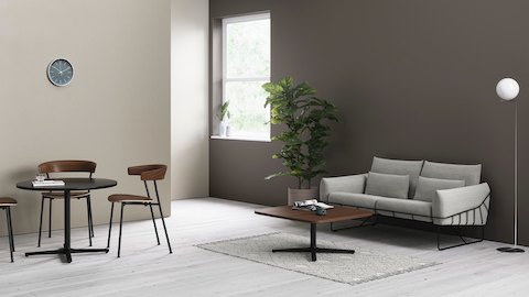 Two Everywhere Tables in an informal seating area, with wooden Leeway Chairs and a grey Wireframe Sofa.