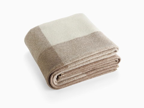 A folded Girard Throw blanket in shades of beige and ivory.