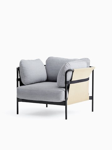 Una silla lounge Can de HAY con tapicería en tela gris claro y estructura en negro con eslinga en color blanquecino, vista desde un leve ángulo de frente.