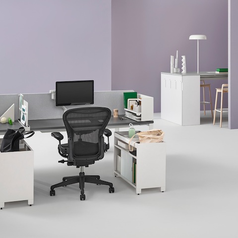 An office setting with two Layout Studio benches with gray fabric center privacy screens, Ubi Work Tools, Tu credenzas, and Aeron and Setu Chairs.