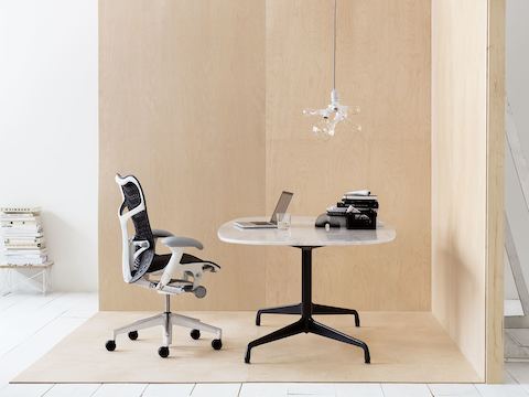 Silla de oficina Mirra 2 negra con una mesa ovalada Eames.