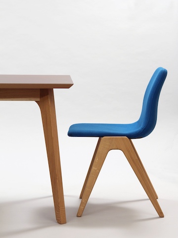 A side view of a blue Viv Wood Chair sitting at the end of a NaughtOne Dalby Conference Table.