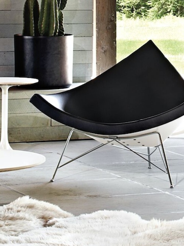 A black leather Nelson Coconut Lounge Chair on an outdoor patio. 