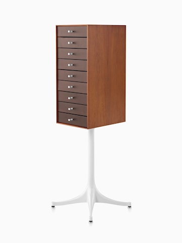 Angled view of a vertical nine-drawer Nelson Miniature Chest with a medium finish and white pedestal base. 
