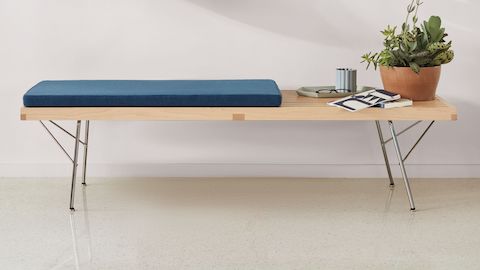 Maple Nelson Platform Bench with metal legs and cushion and items stacked on top, viewed from the front.