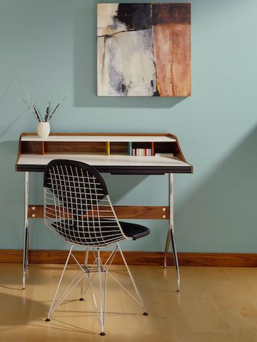 A residential workspace outfitted with an Nelson Swag Leg Desk and an Eames Wire Chair with a black bikini pad.