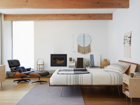 A Nelson Thin Edge bedside table in a contemporary bedroom that also features an Eames Lounge Chair and Ottoman.
