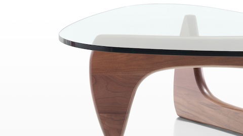 A Noguchi occasional table with a freeform glass top and curved wood base in a medium finish. 