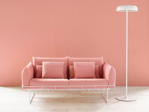 A white Ode floor lamp next to a salmon-colored Wireframe Sofa.