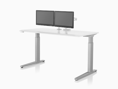 Two Ollin Monitor Arms, one connected to a Flo Power Hub, elevate a pair of monitors off the surface of a sit-to-stand table.