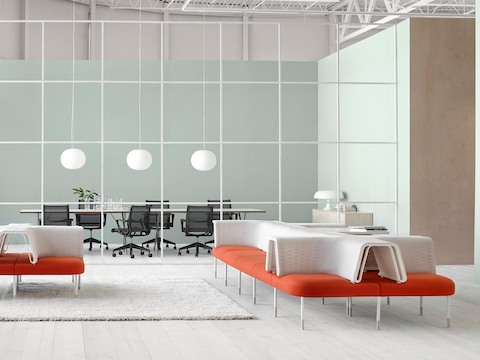 Una configuración Public Office Landscape con configuraciones de sillas sociales de color naranja y blanco para apoyar la interacción casual.