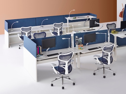 Two groupings of Renew Link standing desk systems with blue Mirra 2 office chairs, white work surfaces, and blue fabric divider panels. Two of the nine desks are raised to standing height.