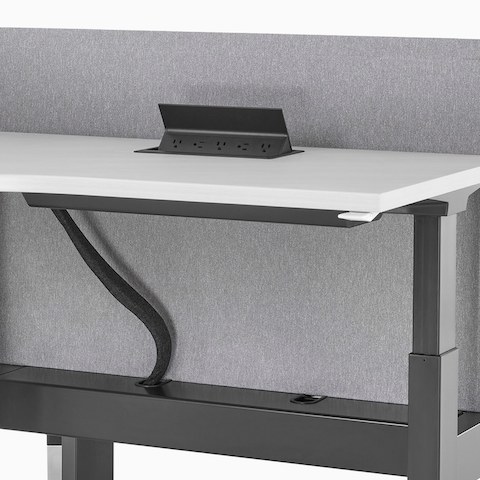 A close-up view of a Renew Link standing desk system with work surface power access and under-surface cable management. 
