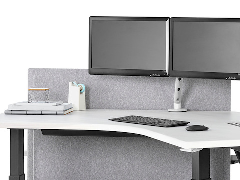 A close-up view of a Renew Link standing desk system with 120-degree work surfaces, black legs, and light gray divider panel. Select to go to the Renew Link standing desk system's specs page.