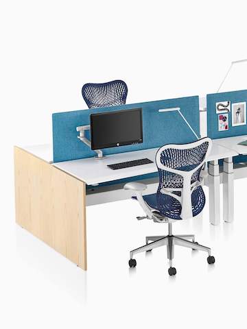 A close-up view of a Renew Link standing desk system with blue Mirra 2 office chairs and blue fabric divider panels. 