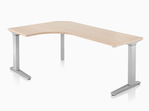 Viewed at an angle, a 90-degree extended corner Renew Sit-to-Stand Table at a standing height, with a metallic silver C-leg base.