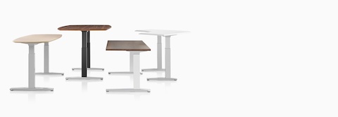 Four Renew Sit-to-Stand Tables in various shapes and top finishes, positioned at various heights.