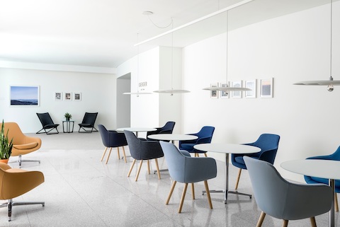 A casual gathering space featuring orange Saiba Lounge Chairs, black Scissor Chairs, and Saiba Side Chairs in shades of blue.
