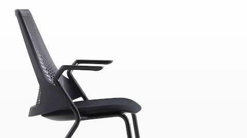 Profile view of a black Sayl Side Chair with a suspension back and upholstered seat.
