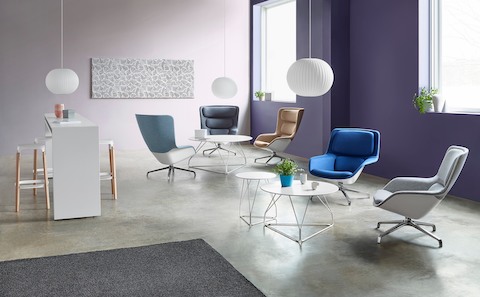 A sitting area featuring five Striad Lounge Chairs in shades of blue, beige, and gray, as well as round Polygon Wire Tables.