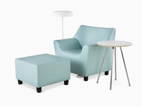 A Swoop Club Chair and Ottoman in a light green upholstery. A Swoop Work Table with a white top and chrome base. An Ode floor lamp in white. The Swoop Club Chair has an optional power unit and housing.