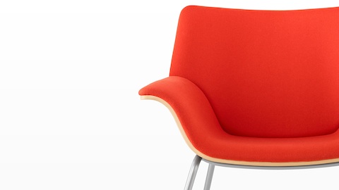 Close view of the sweeping curves on a red-upholstered Swoop lounge chair.