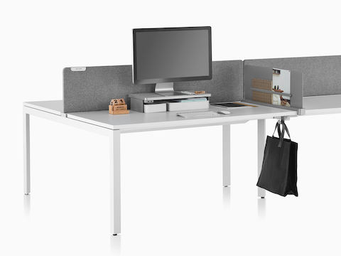 Una superficie de trabajo equipada con Ubi Work Tools, que incluye un estante de la plataforma del monitor, una pantalla delgada y un gancho para la bolsa.
