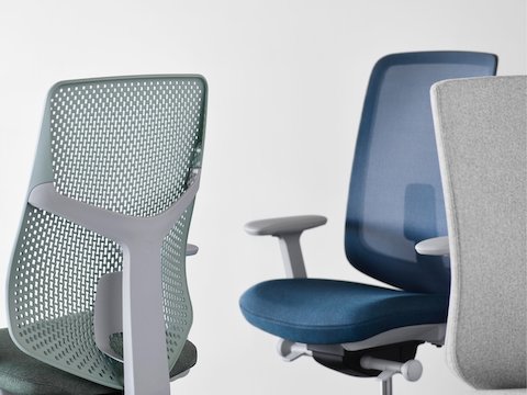 A close-up view of a Verus Chair with a green Triflex back, a Verus Chair with a blue upholstered seat and blue suspension back, and a Verus Chair with a gray upholstered back.