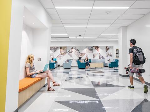University students study admist bench and lounge seating within a corridor. 