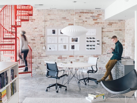 An open workspace with a red spiral staircase and pendant light. 