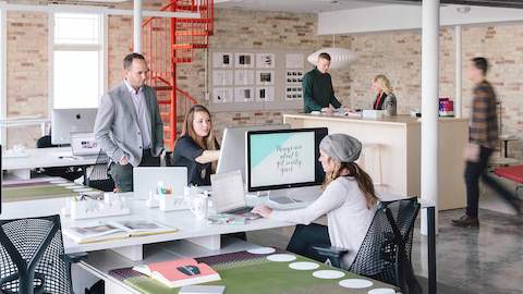 People work and converse inside of an open office space with several Sayl chairs. 