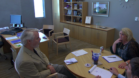 A CEO holding a discussion inside his office furnished with Geiger casegoods.