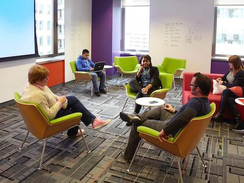 Office employees hold a discussion inside a collaborative space. 