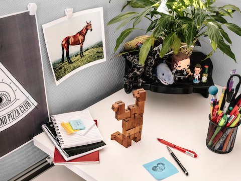 A desk space with notebooks, pens, and various personal items on the surface. 