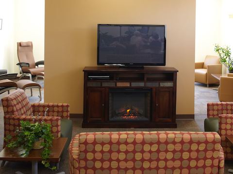A lounge area centered around an electric fireplace and televison. 