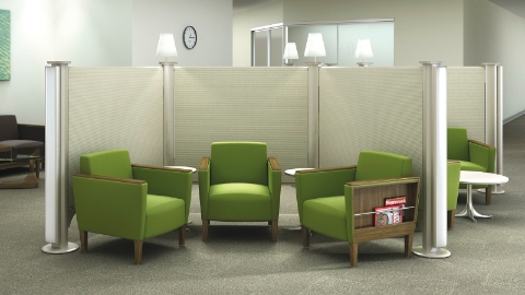 Green chairs sit within a divided waiting area inside a waiting room. 