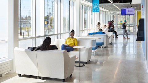 A lounge and booth style seating in the transition area of the building with several students conversing, studying, and lounging.
