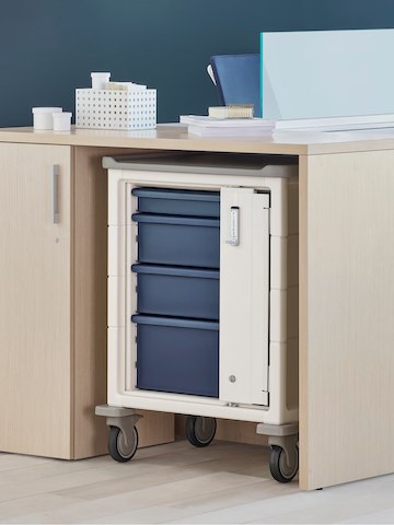 A Procedure and Supply Cart with keyless lock and blue drawers in a storage cove within an Ethospace Nurses Station.