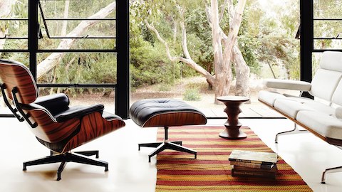 A residential lounge with an Eames Lounge Chair and Ottoman and Eames Sofa. Select to learn about designers Charles and Ray Eames.