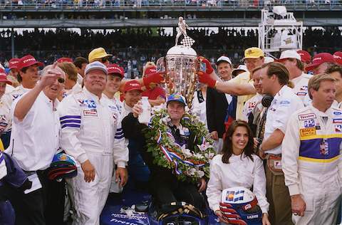 1996 Indianapolis 500 winner Buddy Lazier poses in victory lane with members of the Hemelgarn Racing team and his wife, Kara Lazier. His injured back made it too painful for him to stand during the celebration, so he received his ceremonial bottle of milk while seated on his car.
