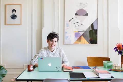Designer Alex Proba works on her computer while sitting at a table in her home.
